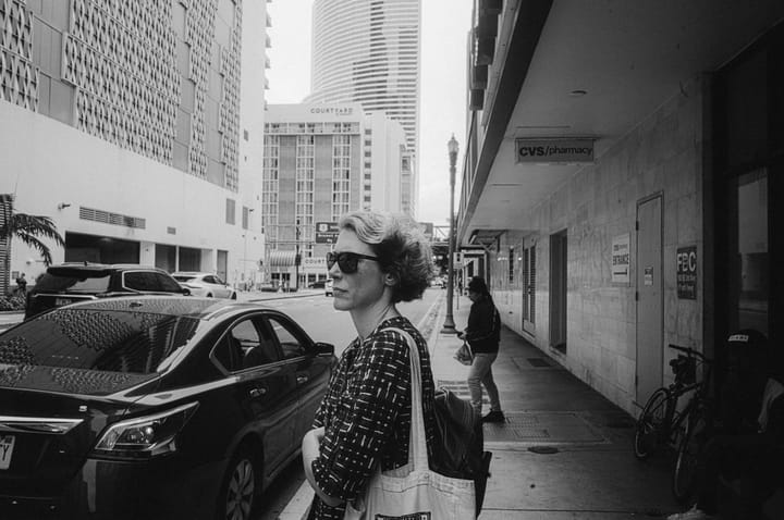 A woman is waiting in front of a building.